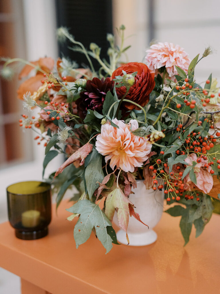 Stunning bar arrangement for an outdoor cocktail hour at a private home in Nashville, TN. Flower-forward, colorful bursts of peach, red and pink were highlighted with gorgeous dahlias, ranunculus, lisianthus, chocolate and pink butterfly ranunculus, copper zinnias, marigolds, rudbeckia, explosion grass, liquid amber, clematis and fall foliage. Design by Rosemary and Finch Floral Design in Nashville, TN. 