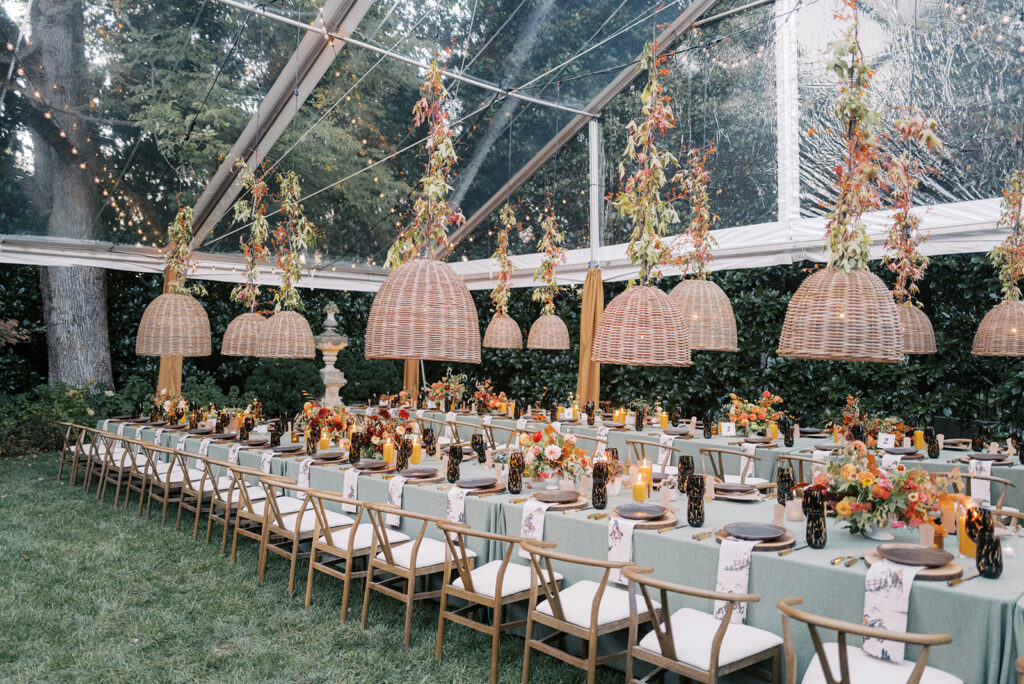 Gorgeous, flower-forward centerpiece arrangements for a private birthday party in Nashville, TN. Autumnal hues of red, brown, orange, pinks and cream are showcased in a stunning display of dahlias, zinnias, ranunculus, nigella, viburnum, rudbeckia, marigolds, liquid amber, spray roses, geranium, rose hips and bittersweet. Fall foliage provides greenery for arrangements and are wrapped around each tent pole and pendant. Design by Rosemary and Finch Floral Design in Nashville, TN. 