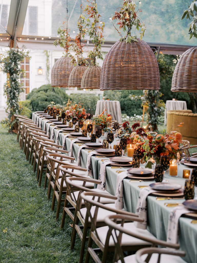 Gorgeous, flower-forward centerpiece arrangements for a private birthday party in Nashville, TN. Autumnal hues of red, brown, orange, pinks and cream are showcased in a stunning display of dahlias, zinnias, ranunculus, nigella, viburnum, rudbeckia, marigolds, liquid amber, spray roses, geranium, rose hips and bittersweet. Fall foliage provides greenery for arrangements and are wrapped around each tent pole and pendant. Design by Rosemary and Finch Floral Design in Nashville, TN. 