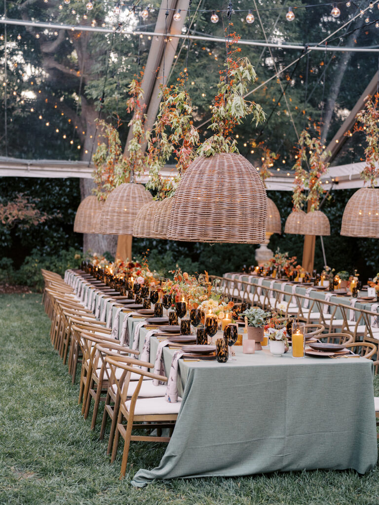 Gorgeous, flower-forward centerpiece arrangements for a private birthday party in Nashville, TN. Autumnal hues of red, brown, orange, pinks and cream are showcased in a stunning display of dahlias, zinnias, ranunculus, nigella, viburnum, rudbeckia, marigolds, liquid amber, spray roses, geranium, rose hips and bittersweet. Fall foliage provides greenery for arrangements and are wrapped around each tent pole and pendant. Design by Rosemary and Finch Floral Design in Nashville, TN. 
