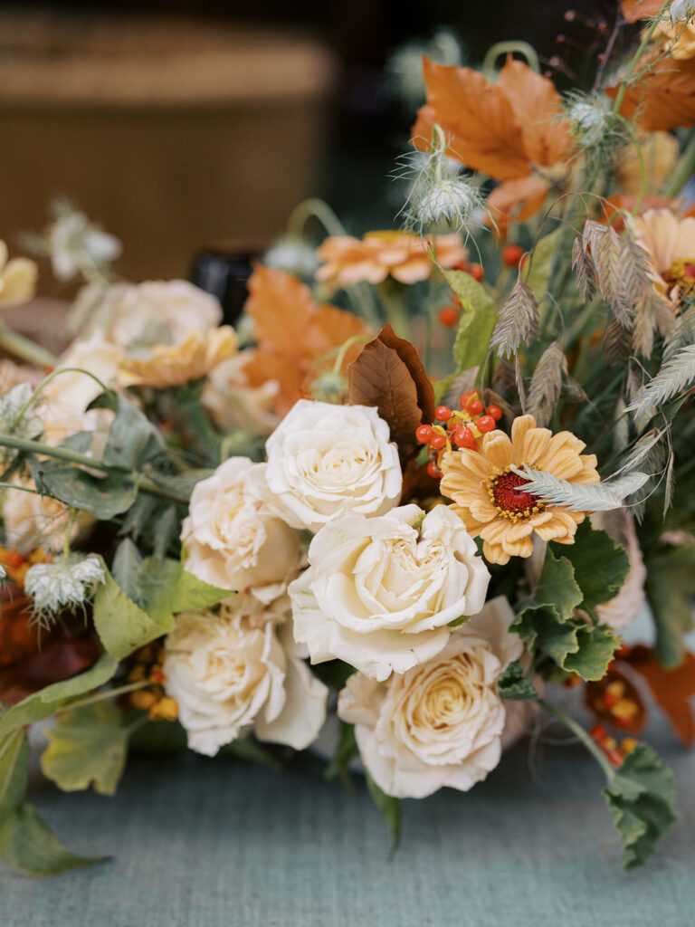 Gorgeous, flower-forward centerpiece arrangements for a private birthday party in Nashville, TN. Autumnal hues of red, brown, orange, pinks and cream are showcased in a stunning display of dahlias, zinnias, ranunculus, nigella, viburnum, rudbeckia, marigolds, liquid amber, spray roses, geranium, rose hips and bittersweet. Fall foliage provides greenery for arrangements and are wrapped around each tent pole and pendant. Design by Rosemary and Finch Floral Design in Nashville, TN. 