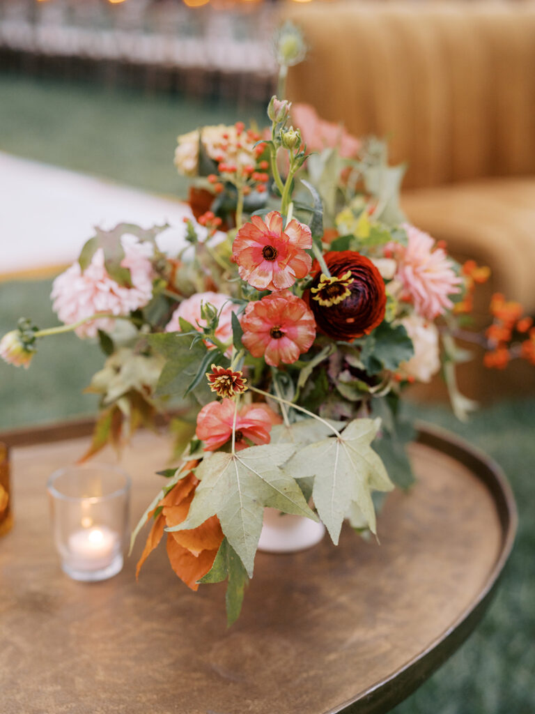 Gorgeous, flower-forward centerpiece arrangements for a private birthday party in Nashville, TN. Autumnal hues of red, brown, orange, pinks and cream are showcased in a stunning display of dahlias, zinnias, ranunculus, nigella, viburnum, rudbeckia, marigolds, liquid amber, spray roses, geranium, rose hips and bittersweet. Fall foliage provides greenery for arrangements and are wrapped around each tent pole and pendant. Design by Rosemary and Finch Floral Design in Nashville, TN. 