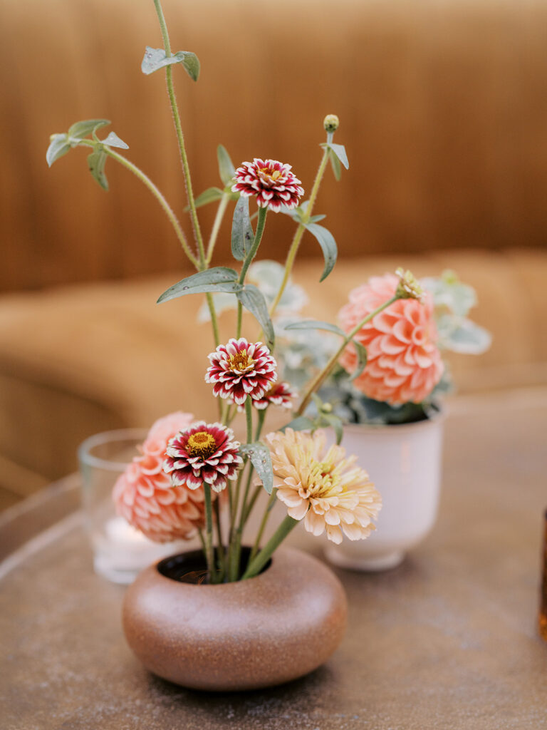 Stunning, autumnal ikebana centerpieces for a private birthday party in Nashville, TN. Each arrangement holds varying clusters of peach, burgundy and orange dahlias, spray roses, nigella, clematis pods, copper zinnias, red gem marigolds, salmon sweet peas, brown ranunculus, rose hips, explosion grass and lisianthus. Bright colors draw the eye to a beautiful table display surrounded by warm tea lights and woven pendants above. Design by Rosemary and Finch Floral Design in Nashville, TN. 