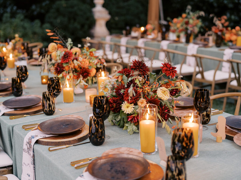 Gorgeous, flower-forward centerpiece arrangements for a private birthday party in Nashville, TN. Autumnal hues of red, brown, orange, pinks and cream are showcased in a stunning display of dahlias, zinnias, ranunculus, nigella, viburnum, rudbeckia, marigolds, liquid amber, spray roses, geranium, rose hips and bittersweet. Fall foliage provides greenery for arrangements and are wrapped around each tent pole and pendant. Design by Rosemary and Finch Floral Design in Nashville, TN. 