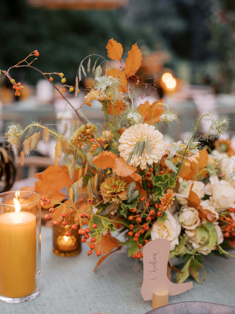 Gorgeous, flower-forward centerpiece arrangements for a private birthday party in Nashville, TN. Autumnal hues of red, brown, orange, pinks and cream are showcased in a stunning display of dahlias, zinnias, ranunculus, nigella, viburnum, rudbeckia, marigolds, liquid amber, spray roses, geranium, rose hips and bittersweet. Fall foliage provides greenery for arrangements and are wrapped around each tent pole and pendant. Design by Rosemary and Finch Floral Design in Nashville, TN. 