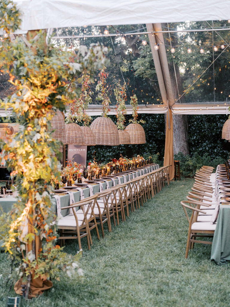 Gorgeous, flower-forward centerpiece arrangements for a private birthday party in Nashville, TN. Autumnal hues of red, brown, orange, pinks and cream are showcased in a stunning display of dahlias, zinnias, ranunculus, nigella, viburnum, rudbeckia, marigolds, liquid amber, spray roses, geranium, rose hips and bittersweet. Fall foliage provides greenery for arrangements and are wrapped around each tent pole and pendant. Design by Rosemary and Finch Floral Design in Nashville, TN. 