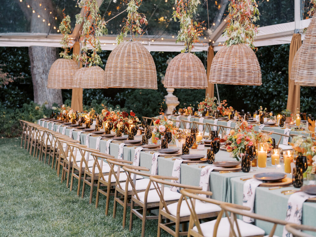 Gorgeous, flower-forward centerpiece arrangements for a private birthday party in Nashville, TN. Autumnal hues of red, brown, orange, pinks and cream are showcased in a stunning display of dahlias, zinnias, ranunculus, nigella, viburnum, rudbeckia, marigolds, liquid amber, spray roses, geranium, rose hips and bittersweet. Fall foliage provides greenery for arrangements and are wrapped around each tent pole and pendant. Design by Rosemary and Finch Floral Design in Nashville, TN. 