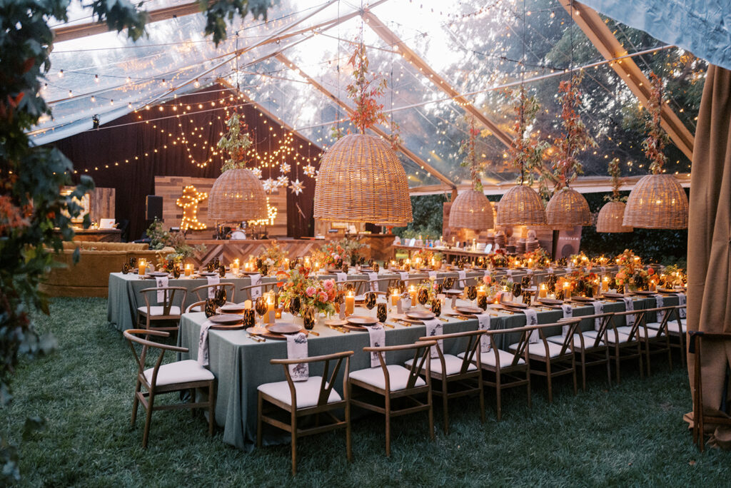 Gorgeous, flower-forward centerpiece arrangements for a private birthday party in Nashville, TN. Autumnal hues of red, brown, orange, pinks and cream are showcased in a stunning display of dahlias, zinnias, ranunculus, nigella, viburnum, rudbeckia, marigolds, liquid amber, spray roses, geranium, rose hips and bittersweet. Fall foliage provides greenery for arrangements and are wrapped around each tent pole and pendant. Design by Rosemary and Finch Floral Design in Nashville, TN. 