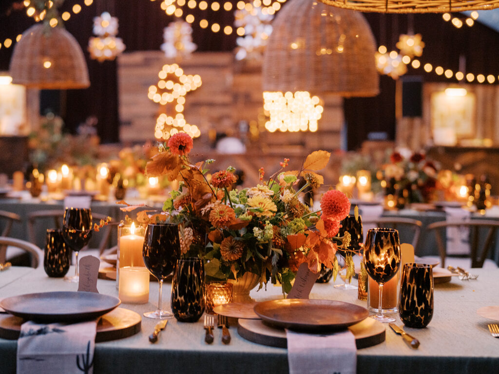 Gorgeous, flower-forward centerpiece arrangements for a private birthday party in Nashville, TN. Autumnal hues of red, brown, orange, pinks and cream are showcased in a stunning display of dahlias, zinnias, ranunculus, nigella, viburnum, rudbeckia, marigolds, liquid amber, spray roses, geranium, rose hips and bittersweet. Fall foliage provides greenery for arrangements and are wrapped around each tent pole and pendant. Design by Rosemary and Finch Floral Design in Nashville, TN. 