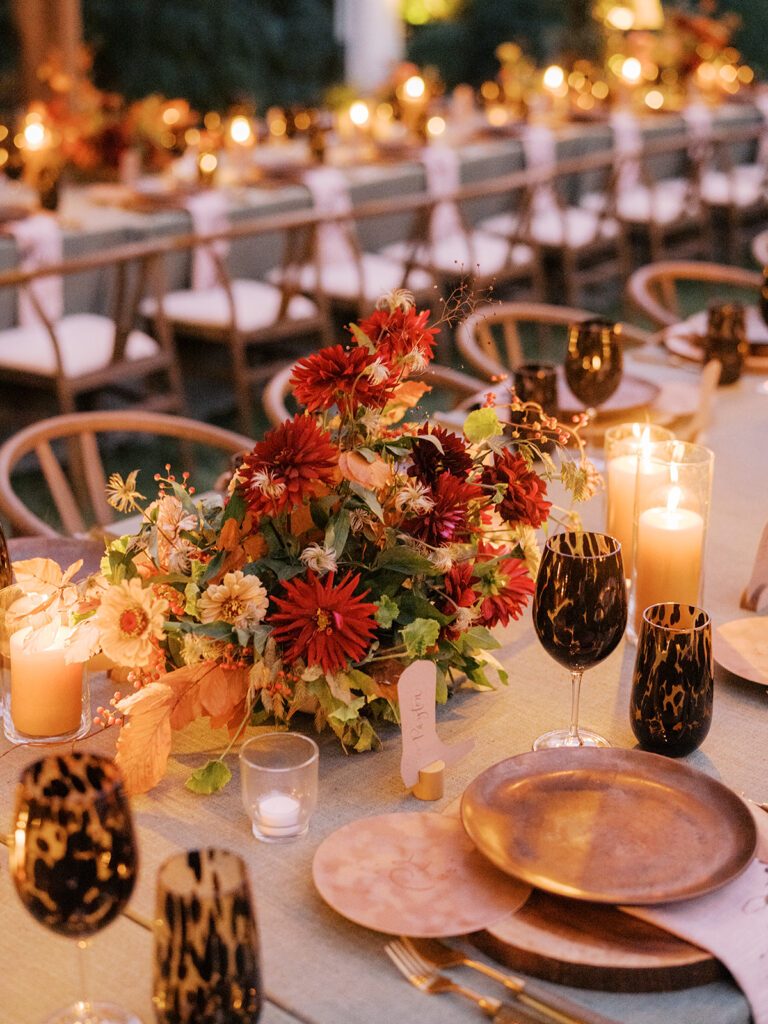 Gorgeous, flower-forward centerpiece arrangements for a private birthday party in Nashville, TN. Autumnal hues of red, brown, orange, pinks and cream are showcased in a stunning display of dahlias, zinnias, ranunculus, nigella, viburnum, rudbeckia, marigolds, liquid amber, spray roses, geranium, rose hips and bittersweet. Fall foliage provides greenery for arrangements and are wrapped around each tent pole and pendant. Design by Rosemary and Finch Floral Design in Nashville, TN. 
