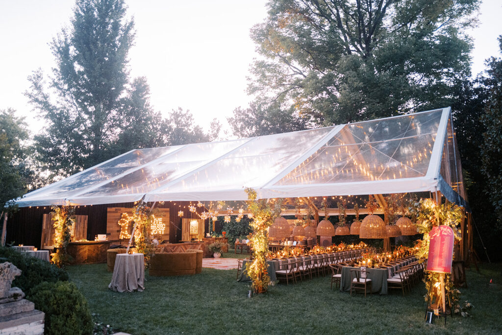 Gorgeous, flower-forward centerpiece arrangements for a private birthday party in Nashville, TN. Autumnal hues of red, brown, orange, pinks and cream are showcased in a stunning display of dahlias, zinnias, ranunculus, nigella, viburnum, rudbeckia, marigolds, liquid amber, spray roses, geranium, rose hips and bittersweet. Fall foliage provides greenery for arrangements and are wrapped around each tent pole and pendant. Design by Rosemary and Finch Floral Design in Nashville, TN. 
