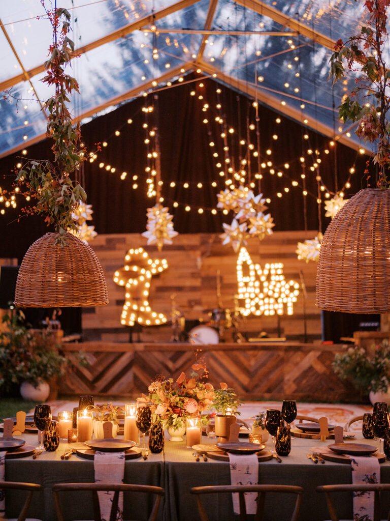 Gorgeous, flower-forward centerpiece arrangements for a private birthday party in Nashville, TN. Autumnal hues of red, brown, orange, pinks and cream are showcased in a stunning display of dahlias, zinnias, ranunculus, nigella, viburnum, rudbeckia, marigolds, liquid amber, spray roses, geranium, rose hips and bittersweet. Fall foliage provides greenery for arrangements and are wrapped around each tent pole and pendant. Design by Rosemary and Finch Floral Design in Nashville, TN. 