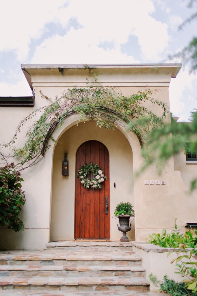 Wedding floral wreaths add a romantic, garden-inspired touch to private home and church doors for a wedding ceremony in Nashville. Designed with white florals and simple greenery, these handcrafted wreaths feature playa blanca roses, quicksand roses, champagne roses, majolikas,  and pieris, creating an elegant and timeless wedding floral statement. Design by Rosemary and Finch Floral Design in Nashville, TN. 