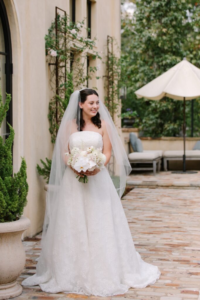 Stunning, elegant flower-forward all-white bridal bouquet with hints of blush and pink for Belle Meade wedding in Nashville. Florals highlighted are phalaenopsis, dahlias, garden roses, majolika roses, ranunculus, butterfly ranunculus, clematis, sweet peas, astilbe, scabiosa and light greenery. The white phalaenopsis creates a soft and bright focal moment for the bouquet. Design by Rosemary and Finch Floral Design in Nashville, TN. 