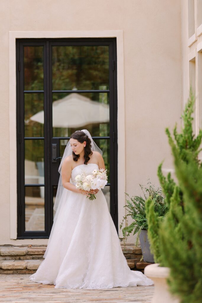 Stunning, elegant flower-forward all-white bridal bouquet with hints of blush and pink for Belle Meade wedding in Nashville. Florals highlighted are phalaenopsis, dahlias, garden roses, majolika roses, ranunculus, butterfly ranunculus, clematis, sweet peas, astilbe, scabiosa and light greenery. The white phalaenopsis creates a soft and bright focal moment for the bouquet. Design by Rosemary and Finch Floral Design in Nashville, TN. 