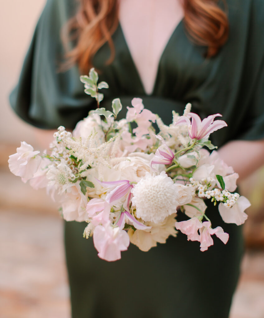 Simple and elegant all-white bridesmaid bouquets with hints of blush and pink for Belle Meade wedding in Nashville. Florals highlighted are dahlias, garden roses, majolika roses, ranunculus, butterfly ranunculus, clematis, sweet peas, astilbe, scabiosa, pieris, saponaria and minimal greenery. The white phalaenopsis creates a soft and bright focal moment for the bouquet. Design by Rosemary and Finch Floral Design in Nashville, TN. 