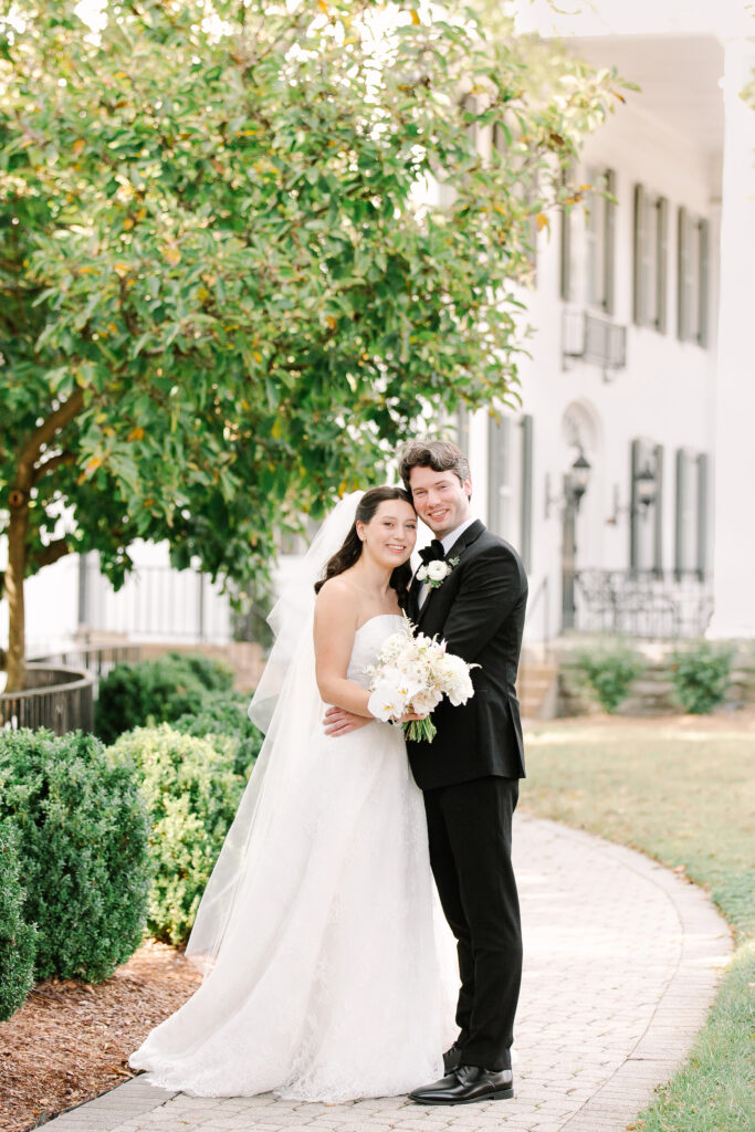 Stunning, elegant flower-forward all-white bridal bouquet with hints of blush and pink for Belle Meade wedding in Nashville. Florals highlighted are phalaenopsis, dahlias, garden roses, majolika roses, ranunculus, butterfly ranunculus, clematis, sweet peas, astilbe, scabiosa and light greenery. The white phalaenopsis creates a soft and bright focal moment for the bouquet. Design by Rosemary and Finch Floral Design in Nashville, TN. 