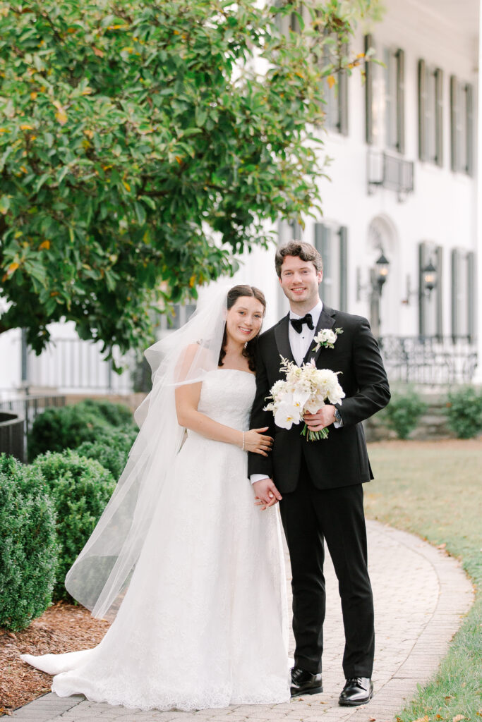 Stunning, elegant flower-forward all-white bridal bouquet with hints of blush and pink for Belle Meade wedding in Nashville. Florals highlighted are phalaenopsis, dahlias, garden roses, majolika roses, ranunculus, butterfly ranunculus, clematis, sweet peas, astilbe, scabiosa and light greenery. The white phalaenopsis creates a soft and bright focal moment for the bouquet. Design by Rosemary and Finch Floral Design in Nashville, TN. 