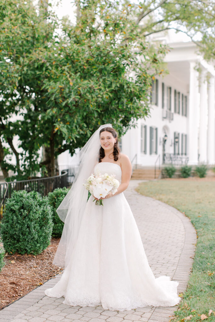 Stunning, elegant flower-forward all-white bridal bouquet with hints of blush and pink for Belle Meade wedding in Nashville. Florals highlighted are phalaenopsis, dahlias, garden roses, majolika roses, ranunculus, butterfly ranunculus, clematis, sweet peas, astilbe, scabiosa and light greenery. The white phalaenopsis creates a soft and bright focal moment for the bouquet. Design by Rosemary and Finch Floral Design in Nashville, TN. 