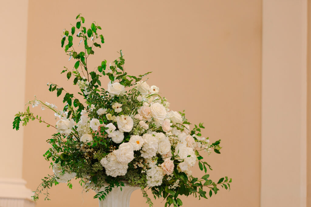 Stunning all-white statement arrangements framing the altar for a Belle Meade wedding in Nashville. Lush flowers with greenery consist of white hydrangeas, dahlias, garden roses, playa blancas, quicksand roses, ranunculus, lisianthus, majolikas, pieris, delphinium and heavy greenery draping over the sides. Elegant focal points for Nashville wedding ceremony. Design by Rosemary and Finch Floral Design in Nashville, TN. 