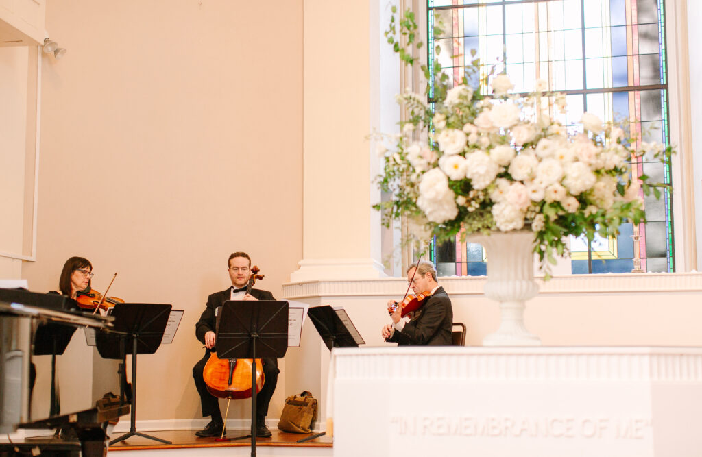Stunning all-white statement arrangements framing the altar for a Belle Meade wedding in Nashville. Lush flowers with greenery consist of white hydrangeas, dahlias, garden roses, playa blancas, quicksand roses, ranunculus, lisianthus, majolikas, pieris, delphinium and heavy greenery draping over the sides. Elegant focal points for Nashville wedding ceremony. Design by Rosemary and Finch Floral Design in Nashville, TN. 