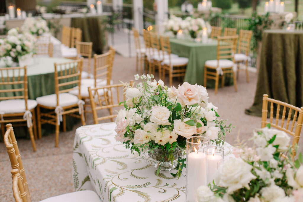 Lush and elegant floral centerpieces for Nashville wedding at Hillwood Country Club. Light pinks, blush and white florals consist of dahlias, garden roses, playa blancas, quicksand roses, ranunculus, lisianthus, majolikas, pieris, delphinium, sweet peas, saponaria, clematis, astilbe, and contrasting greenery. Centerpieces were accompanied by warm candlelight and lush vines growing near the bar for a beautiful wedding reception. Design by Rosemary and Finch Floral Design in Nashville, TN. 