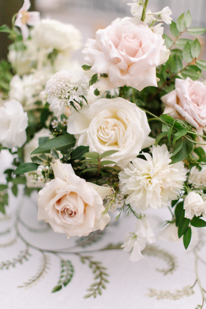 Lush and elegant floral centerpieces for Nashville wedding at Hillwood Country Club. Light pinks, blush and white florals consist of dahlias, garden roses, playa blancas, quicksand roses, ranunculus, lisianthus, majolikas, pieris, delphinium, sweet peas, saponaria, clematis, astilbe, and contrasting greenery. Centerpieces were accompanied by warm candlelight and lush vines growing near the bar for a beautiful wedding reception. Design by Rosemary and Finch Floral Design in Nashville, TN. 