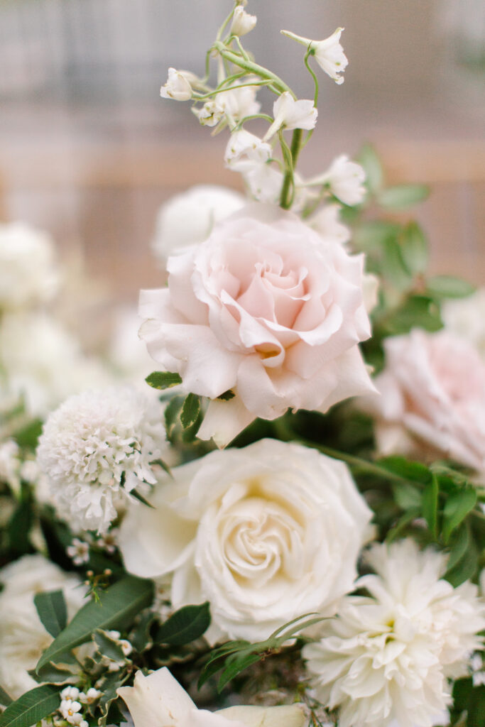 Lush and elegant floral centerpieces for Nashville wedding at Hillwood Country Club. Light pinks, blush and white florals consist of dahlias, garden roses, playa blancas, quicksand roses, ranunculus, lisianthus, majolikas, pieris, delphinium, sweet peas, saponaria, clematis, astilbe, and contrasting greenery. Centerpieces were accompanied by warm candlelight and lush vines growing near the bar for a beautiful wedding reception. Design by Rosemary and Finch Floral Design in Nashville, TN. 