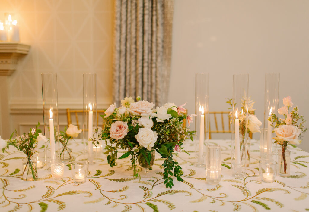 Lush and elegant floral centerpieces for Nashville wedding at Hillwood Country Club. Light pinks, blush and white florals consist of dahlias, garden roses, playa blancas, quicksand roses, ranunculus, lisianthus, majolikas, pieris, delphinium, sweet peas, saponaria, clematis, astilbe, and contrasting greenery. Centerpieces were accompanied by warm candlelight and lush vines growing near the bar for a beautiful wedding reception. Design by Rosemary and Finch Floral Design in Nashville, TN. 