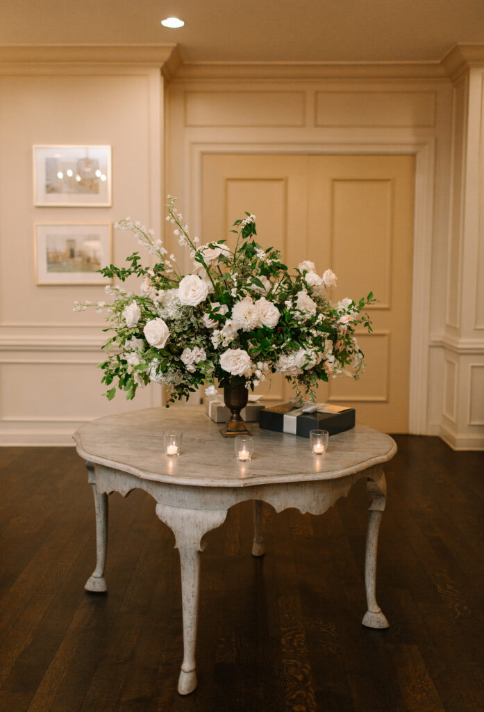 Stunning all-white statement arrangement creating a focal point for the lobby at Hillwood Country Club in Nashville. Lush flowers with greenery consist of white hydrangeas, dahlias, garden roses, playa blancas, quicksand roses, ranunculus, lisianthus, majolikas, pieris, delphinium and heavy greenery draping over the sides. Design by Rosemary and Finch Floral Design in Nashville, TN. 