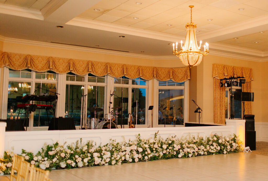 Gorgeous stage-front floral meadows with all-white hydrangeas, dahlias, lisianthus, ranunculus, delphinium, majolikas, champagne roses, playa blanca roses, pieris and lush greenery. Elegant focal point for Nashville wedding reception at Hillwood Country Club. Design by Rosemary anf Finch Floral Design in Nashville, TN.