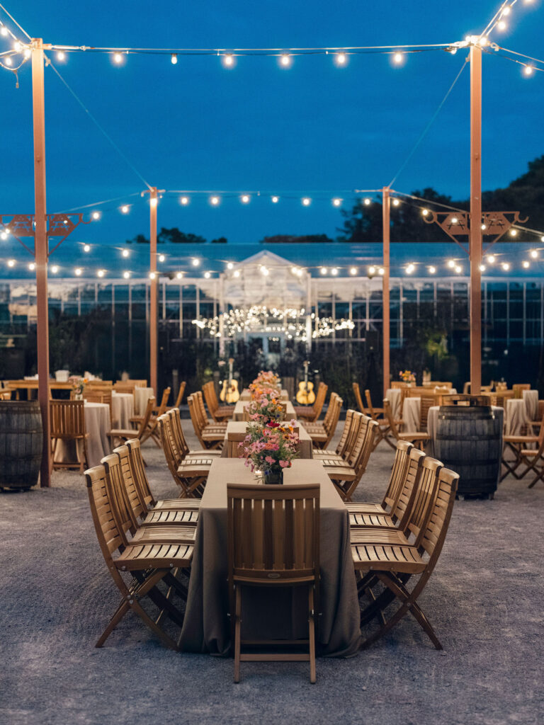 Simple, meadow-like arrangements are scattered on the tables for a southern themed welcome party at Southall Farm and Inn. The florals resemble bunches of wildflowers placed in glass jars and include cosmos, zinnias, cornflowers, yellow solidago riceflower and other wildflowers in an array of pinks, reds, yellows and oranges. Design by Rosemary and Finch Floral Design in Nashville, TN.
