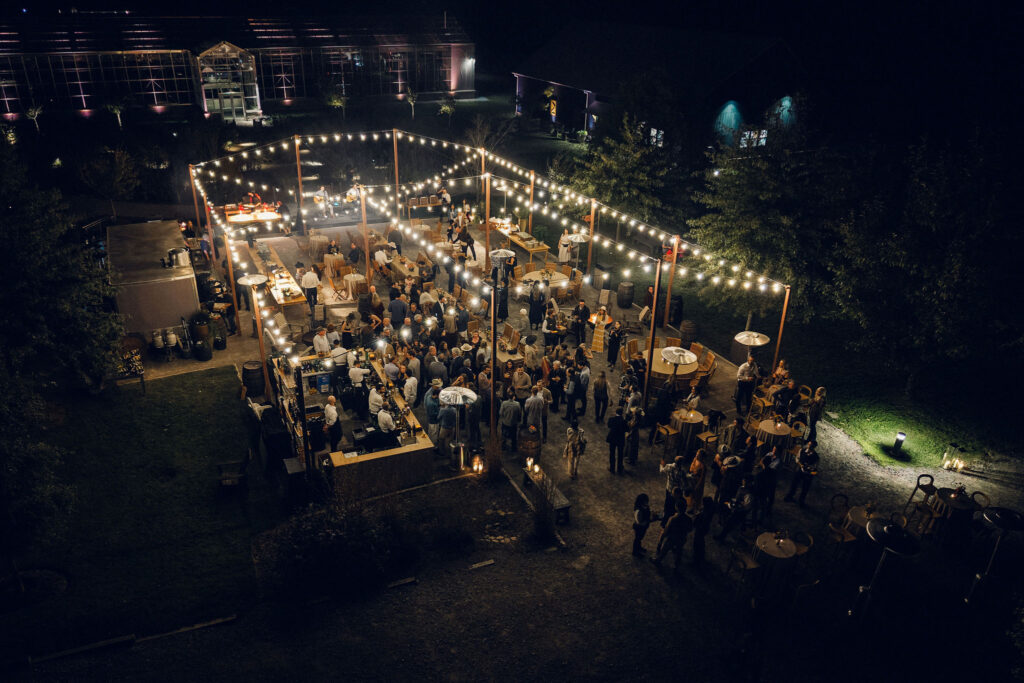 Simple, meadow-like arrangements are scattered on the tables for a southern themed welcome party at Southall Farm and Inn. The florals resemble bunches of wildflowers placed in glass jars and include cosmos, zinnias, cornflowers, yellow solidago riceflower and other wildflowers in an array of pinks, reds, yellows and oranges. Design by Rosemary and Finch Floral Design in Nashville, TN.
