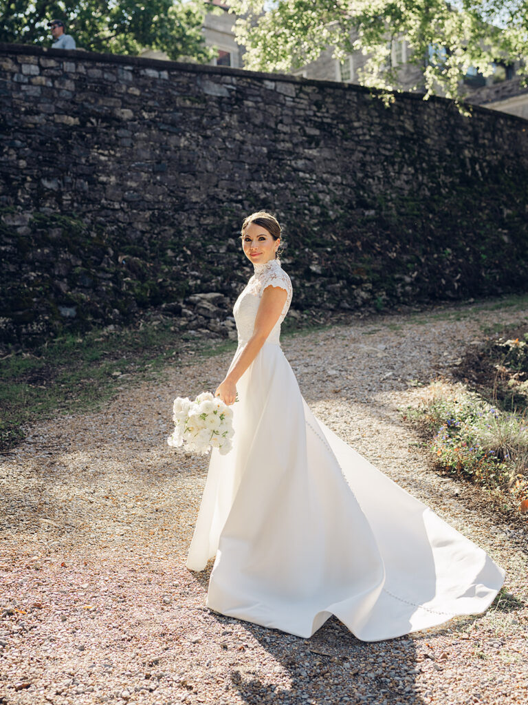 Romantic, editorial bridal bouquet featuring all-white garden roses, cloud roses, sweet peas, spray roses, ranunculus, and lisianthus accompanied by olive branches and light greenery. Soft and romantic bouquet to highlight elegance of a botanical tented wedding at Cheekwood. Design by Rosemary & Finch Floral Design in Nashville, TN.