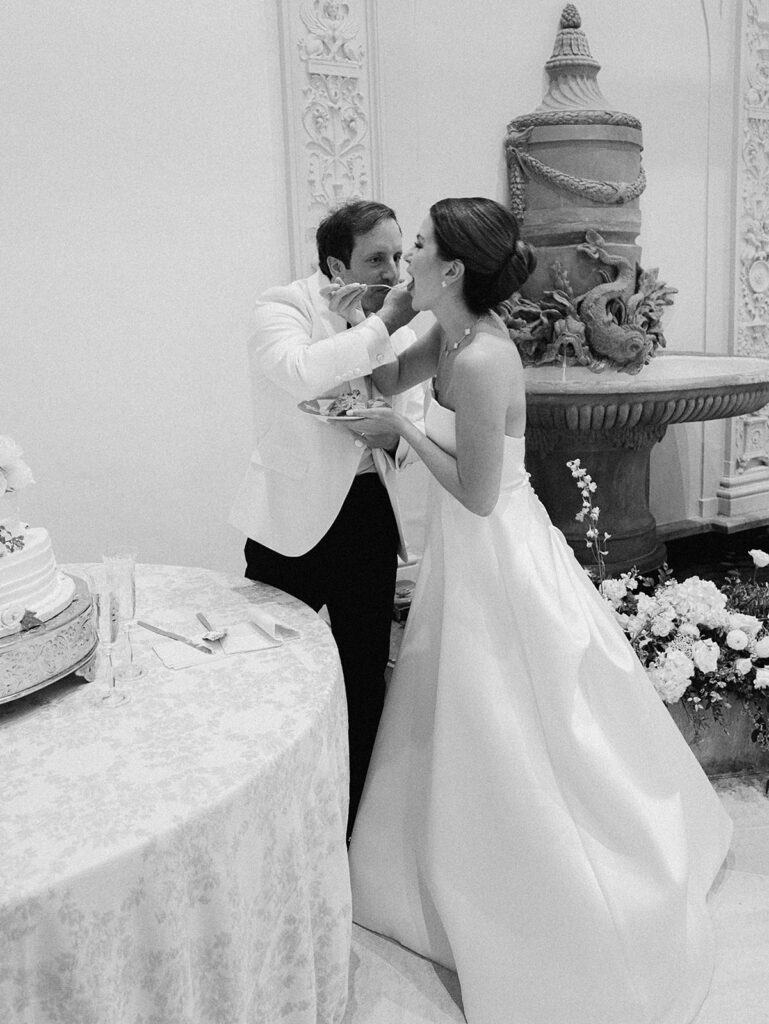 Simple, all-white florals cascade down the side of stunning reception wedding cake. Spray roses, cloud roses, ranunculus, riceflower, olive branches and ivy are used to create a beautiful cake display. Design by Rosemary & Finch Floral Design in Nashville, TN.