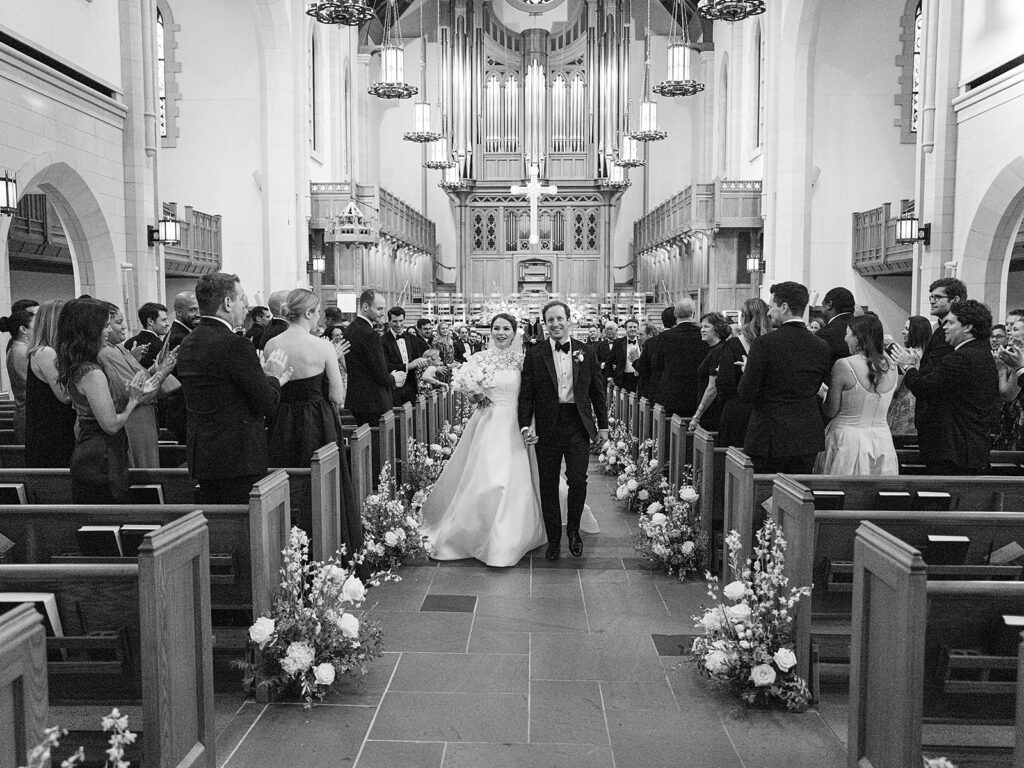 Romantic and elegant aisle meadows are highlighted with all-white garden roses, hydrangeas, spray roses, riceflower, stock and delphinium. Light greenery, including olive branches, create a soft contrast to the meadows. Stunning sanctuary aisle meadows that are repurposed to the dance floor stage meadows. Statement urns at the altar consist of the same flowers and offer a stunning focal point for the ceremony. Design by Rosemary & Finch Floral Design in Nashville, TN.