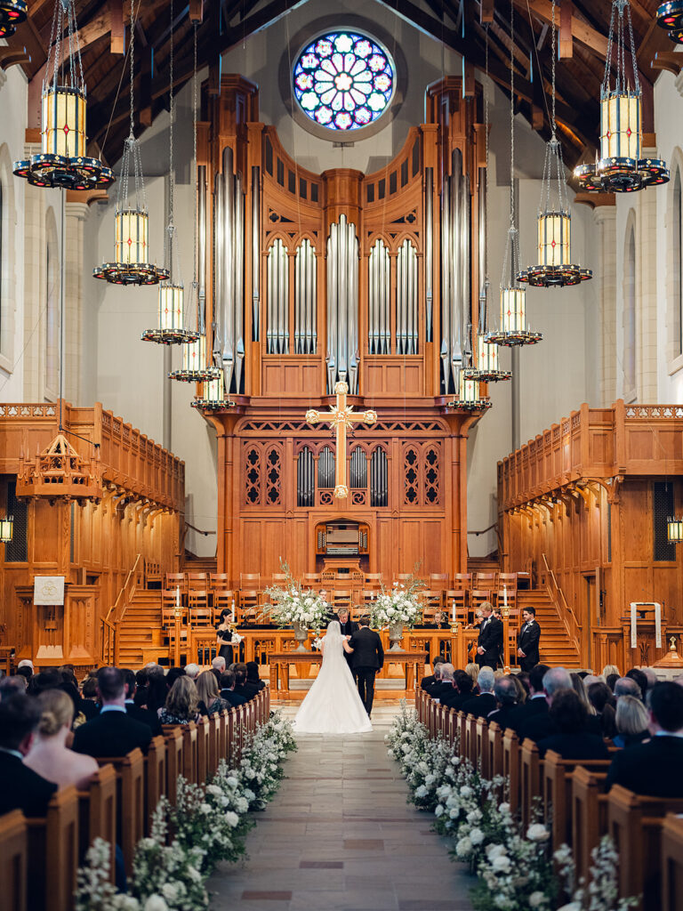 Romantic and elegant aisle meadows are highlighted with all-white garden roses, hydrangeas, spray roses, riceflower, stock and delphinium. Light greenery, including olive branches, create a soft contrast to the meadows. Stunning sanctuary aisle meadows that are repurposed to the dance floor stage meadows. Statement urns at the altar consist of the same flowers and offer a stunning focal point for the ceremony. Design by Rosemary & Finch Floral Design in Nashville, TN.