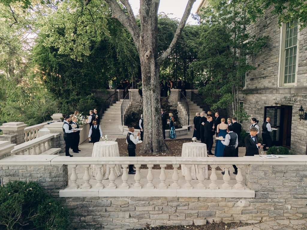 Simple and elegant floral arrangements for Cheekwood cocktail hour consisting of all-white bar arrangements and simple bud vases. Double tulips, hydrangeas, cloud and spray roses, delphinium, allium, riceflower, ranunculus, lisianthus, and white stock are used to create stunning floral moments scattered throughout the cocktail hour patio and bars. Design by Rosemary & Finch Floral Design in Nashville, TN.