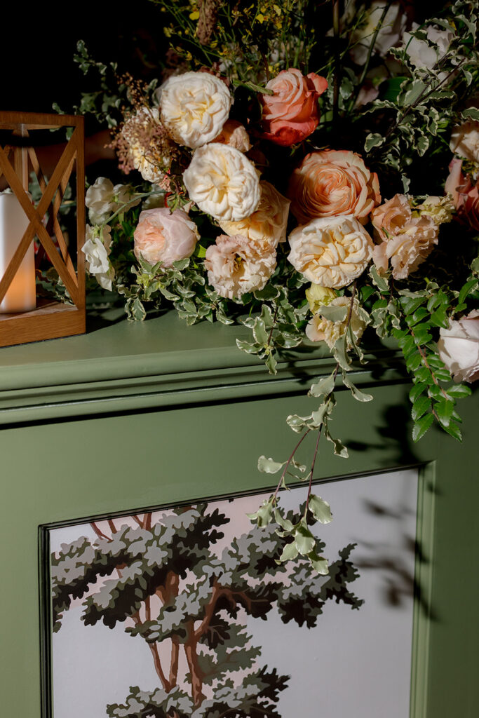 Stunning reception and bar statement arrangements catch the eye of guests at Sewanee, TN wedding. Colorful bursts of garden roses, moab roses, creme de la creme, carnations, spray roses, dahlias, tulips, yarrow, foxglove, zinnias, oncidium orchids, cosmos, smokebush and more are accompanied by soft greens and ferns. Arrangements are drenched in colors of peach, pinks, yellows and green. Design by Rosemary and Finch Floral Design in Nashville, TN. 