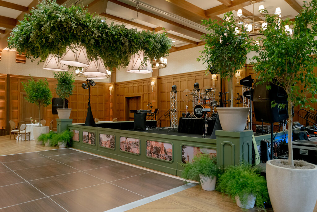 A lush, all-green dance floor installation is suspended in the air surrounding large light pendants. Featuring smilax, huckleberry branches and mini pitt greens, the dance floor has a moody yet lively focal point for guests to enjoy and dance under. Design by Rosemary and Finch Floral Design in Nashville, TN.