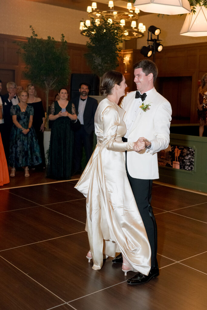 A lush, all-green dance floor installation is suspended in the air surrounding large light pendants. Featuring smilax, huckleberry branches and mini pitt greens, the dance floor has a moody yet lively focal point for guests to enjoy and dance under. Design by Rosemary and Finch Floral Design in Nashville, TN.