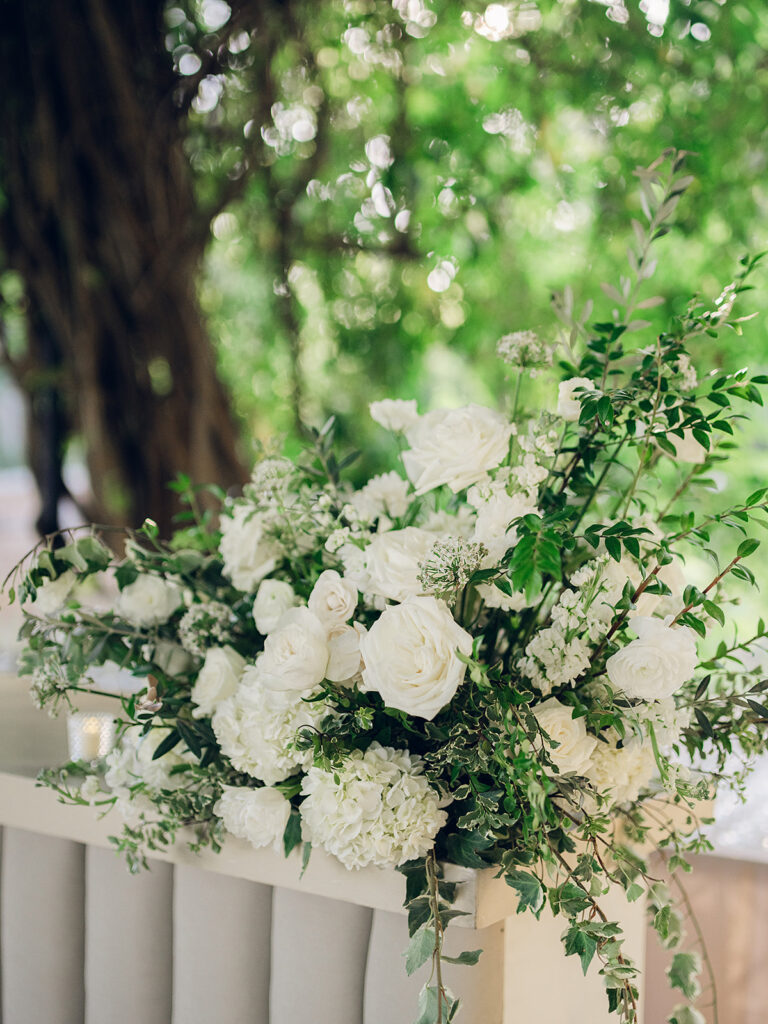 Simple and elegant floral arrangements for Cheekwood cocktail hour consisting of all-white bar arrangements and simple bud vases. Double tulips, hydrangeas, cloud and spray roses, delphinium, allium, riceflower, ranunculus, lisianthus, and white stock are used to create stunning floral moments scattered throughout the cocktail hour patio and bars. Design by Rosemary & Finch Floral Design in Nashville, TN.