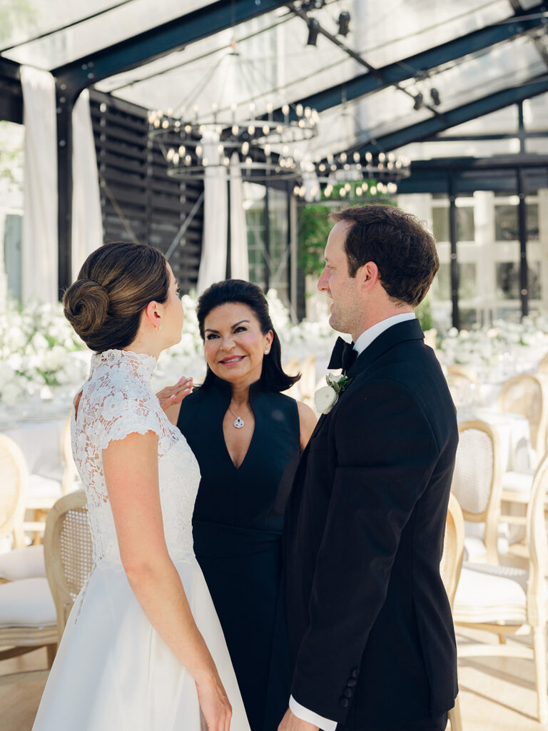 Romantic and stunning glass-tented wedding reception at Cheekwood botanical garden in Nashville, TN. Elegant garden-inspired centerpieces feature lush, all-white cloud roses, hydrangeas, lisianthus, dahlias, sweet peas, double tulips, delphinium, stock, allium, flowering champagne, and more with light greenery. Matching banquette meadows line either side of the glass tent creating a lush and timeless feel. Design by Rosemary & Finch Floral Design in Nashville, TN.